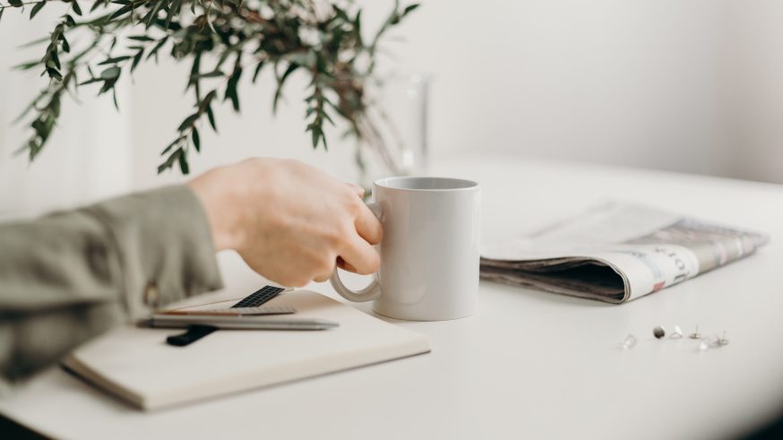 Desk with a newspaper and cup of coffee on it