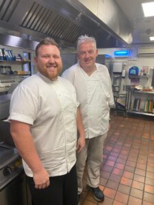 Chefs in whites smiling at the camera