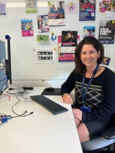 Neena at her desk, smiling at the camera